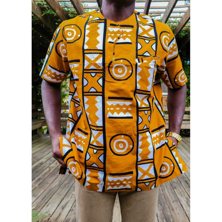 Our Adinkra African Print Short Sleeve Shirt Is An Essential Piece For Men. It Is Perfect For The Modern Man That Enjoys Elevating His African Wardrobe. This Very Stylish Piece Can Be Worn With Jeans Or Slacks To Bring Out The Look. Versatility Of The Design Goes With Any Style Of Wear. Description: Short Sleeve Shirt Hidden Front Pocket 100% African Wax Print Designed In The Usa, Imported From Ghana West African Dark Orange In Color Care Instruction: Dry Clean Only. Do Not Bleach. Iron Inside O Traditional Printed Yellow Tops, Traditional Short Sleeve Shirt With Graphic Print, Traditional Orange Cotton Tops, Mens African Wear Designs, African Print Shirts For Men, Men African Wear, African Wear For Men, African Print Shirt, African Wear Styles For Men