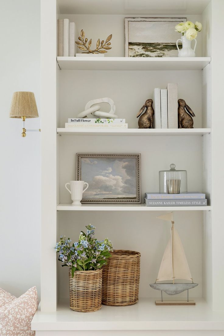 a white book shelf filled with books and vases