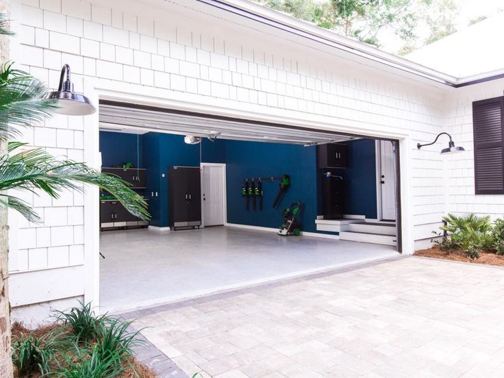 an open garage with blue walls and white brick flooring on the side of it