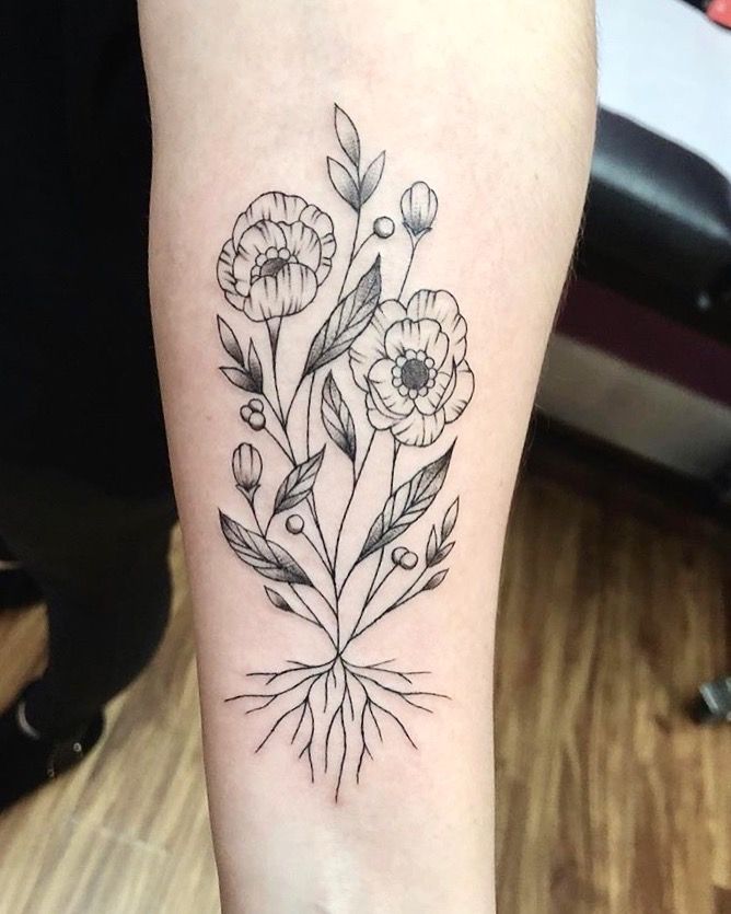 a black and white flower tattoo on the right thigh, with small flowers growing out of it