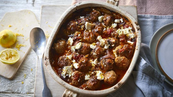 a dish with meatballs and cheese next to a spoon