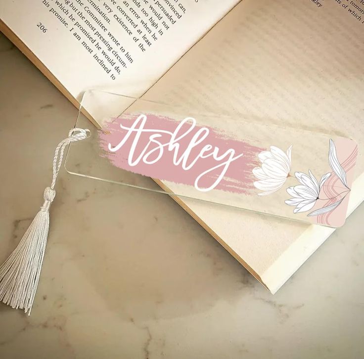 an open book with a tassel hanging from it's cover and the word asley on top