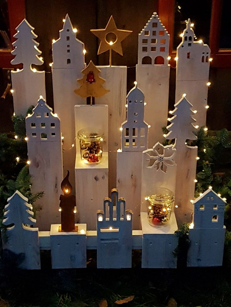 a small christmas village with lights and ornaments on display in front of a window at night