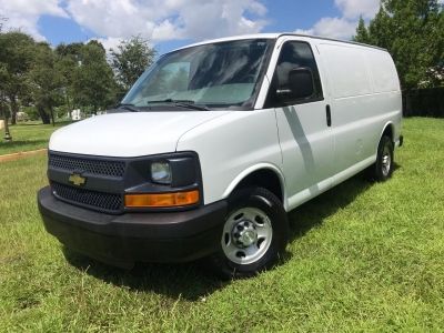 a white van parked on top of a lush green field