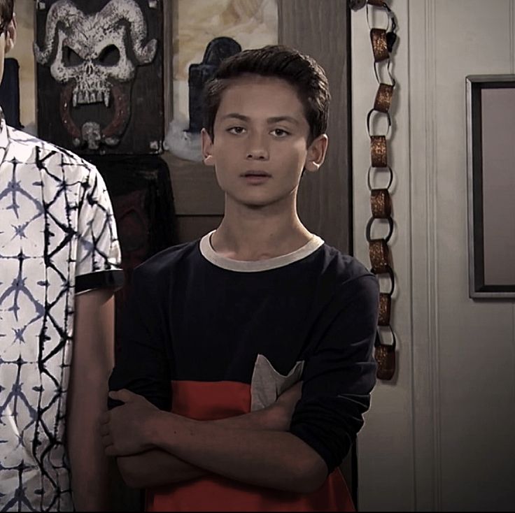 two young men standing next to each other in front of a wall with skulls on it