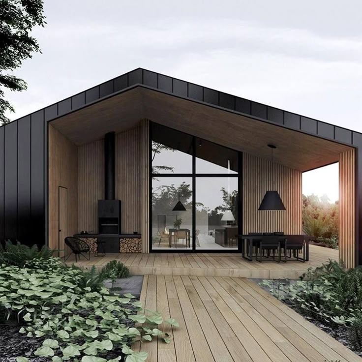 a small house with wooden floors and black accents on the roof is surrounded by greenery