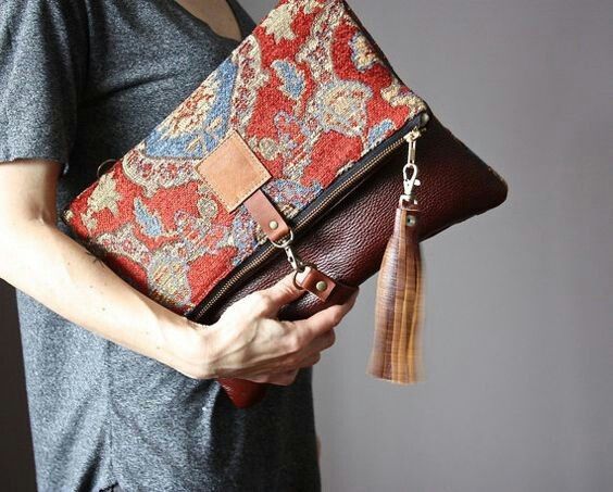 a woman is holding a purse with a tassel