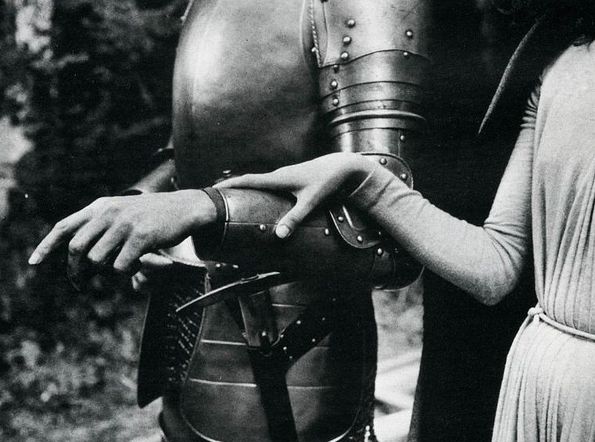 an old photo of two people dressed in medieval costumes and helmets, one holding the arm of another person's hand