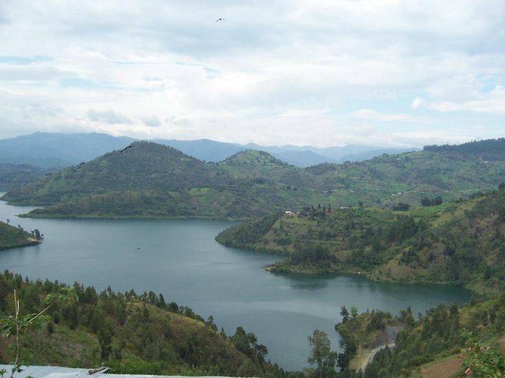 a lake surrounded by lush green mountains under a cloudy sky