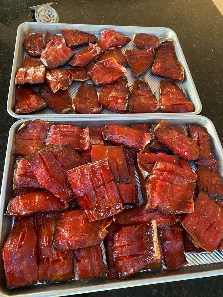 two trays filled with meat sitting on top of a table