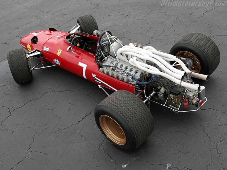 a red race car sitting on top of a parking lot next to a white hose