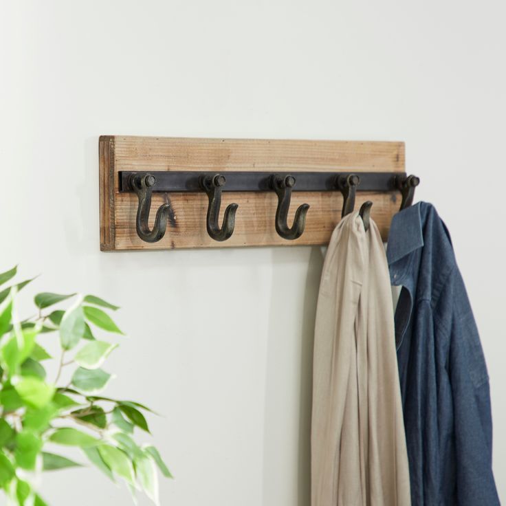 a coat rack with two coats hanging on it and a potted plant next to it