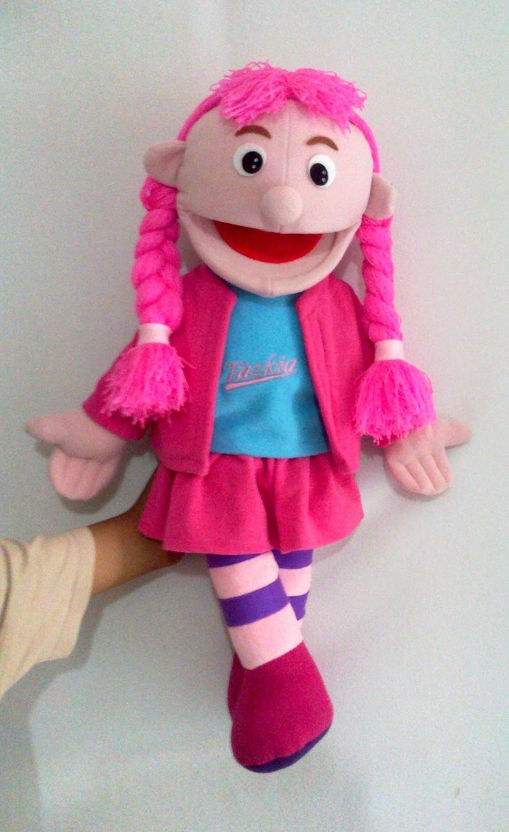 a stuffed animal doll with pink hair and purple socks on it's feet, sitting against a white wall