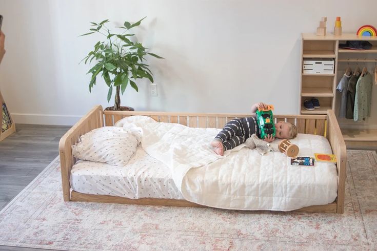 a small child laying on top of a bed in a room with a book shelf