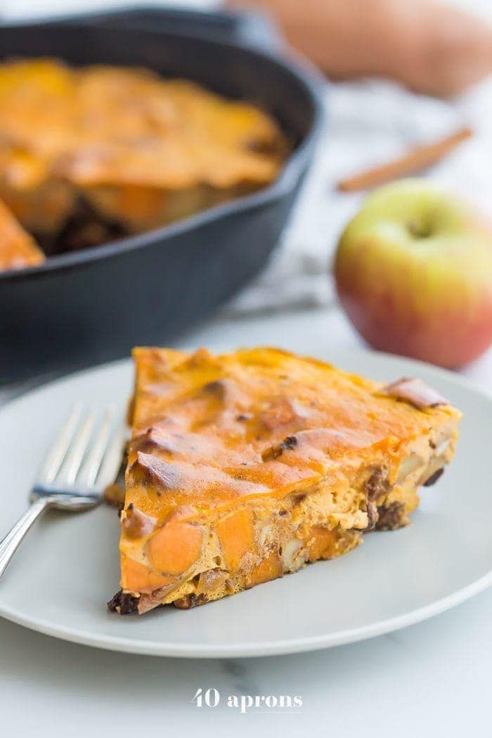 a slice of quiche on a plate with an apple in the background