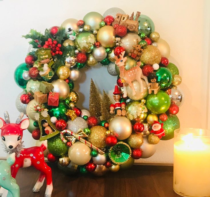 a christmas wreath sitting on top of a table next to a lit candle and a small deer figurine