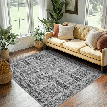 a living room with a couch, rug and potted plants on the hardwood floor