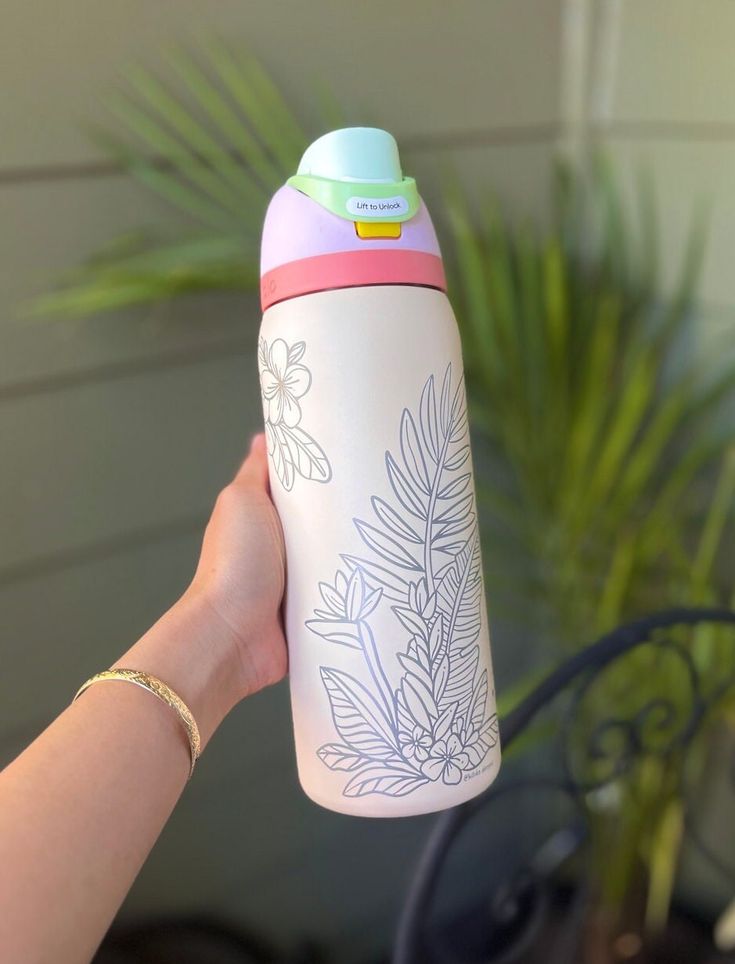 a hand holding a white and pink water bottle