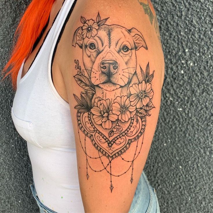 a woman's arm with a dog and flowers tattoo on the left side of her shoulder