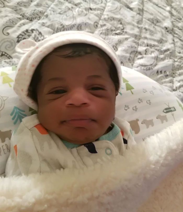 a baby wearing a hat and blanket on top of a bed