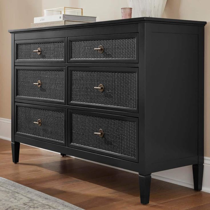 a black dresser with wicker drawers in a room