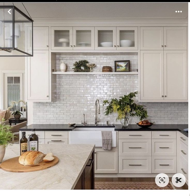 a kitchen with white cabinets and marble counter tops