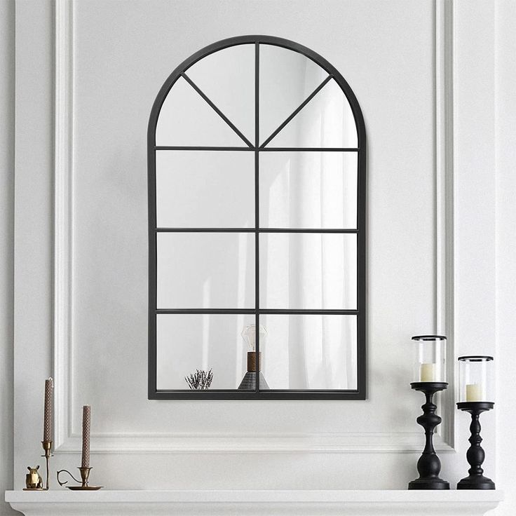 a white fireplace with a mirror and candles on the mantel in front of it