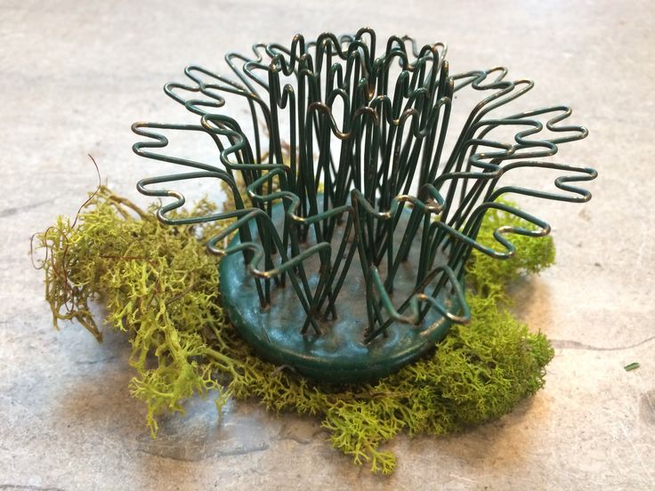 a sculpture made out of wire and moss on the ground with scissors stuck in it