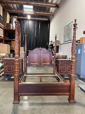 an antique wooden bed frame with four posts in the middle of a room filled with boxes