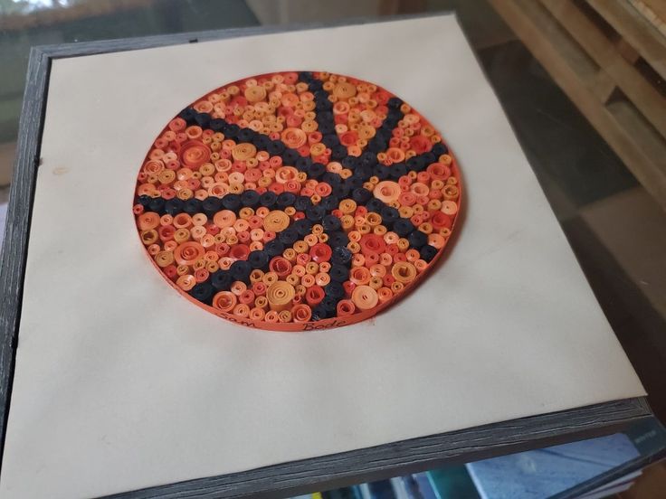 an orange and black object sitting on top of a piece of white paper with holes in it