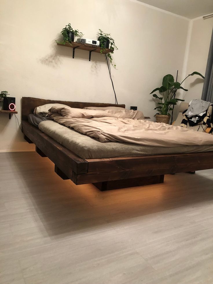 a bed sitting on top of a hard wood floor next to a plant filled wall