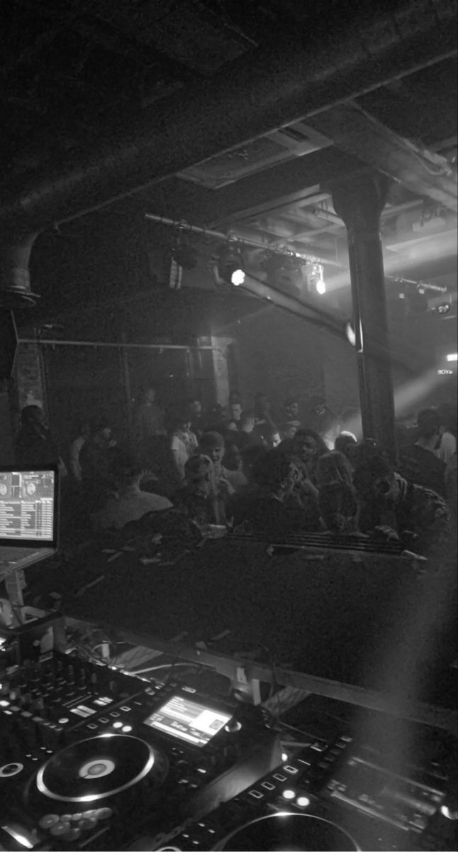 a dj mixing in front of a crowd at a party with lights and sound equipment