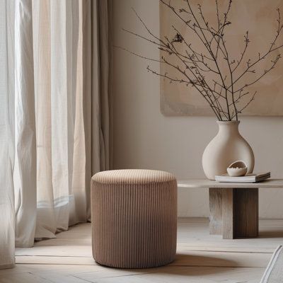 a white vase sitting on top of a table next to a window