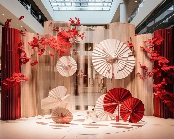 several red and white umbrellas are on display in a room with wooden panels, trees and flowers