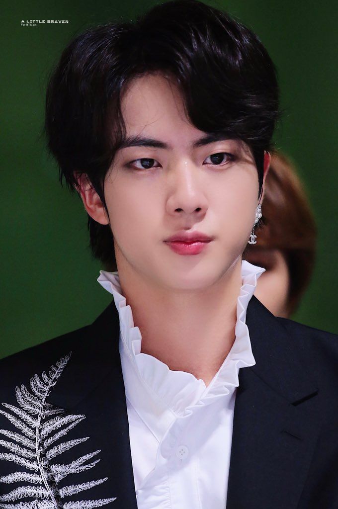 the young man is wearing a black jacket and white shirt with a fern print on it