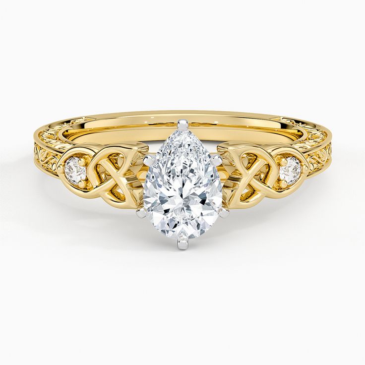 a yellow gold engagement ring with a pear shaped diamond in the center and an intricate band