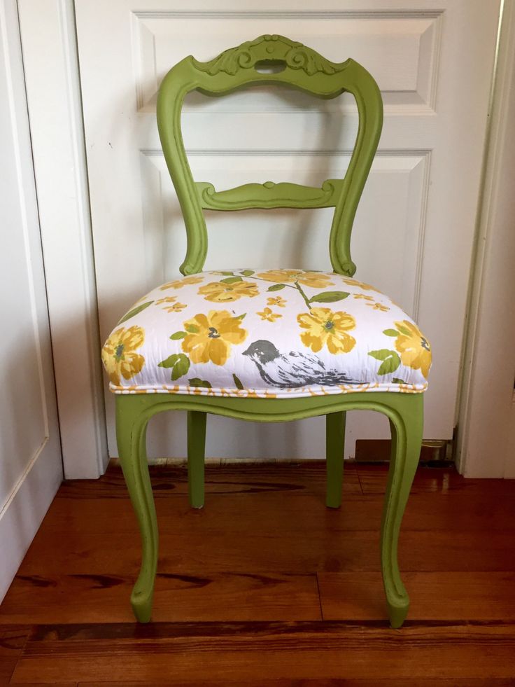 a green chair with yellow flowers on it and a bird pillow sitting on the seat