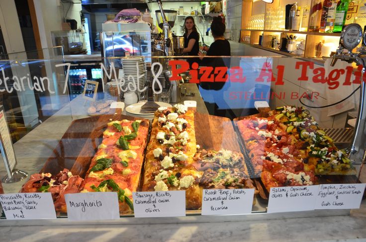 several different types of pizza on display behind glass