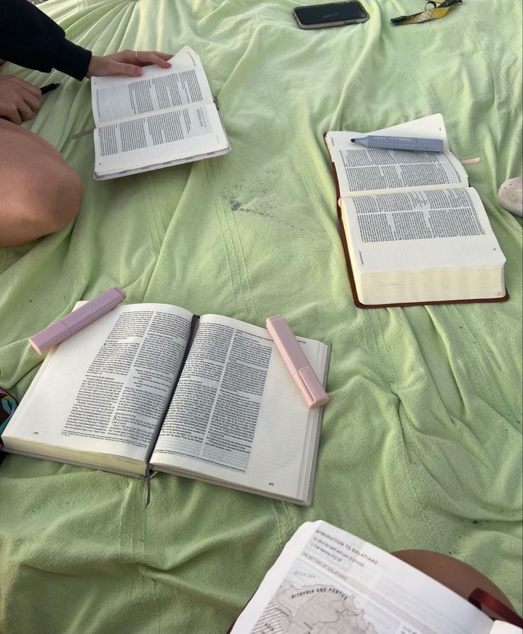 three open books laying on top of a green blanket