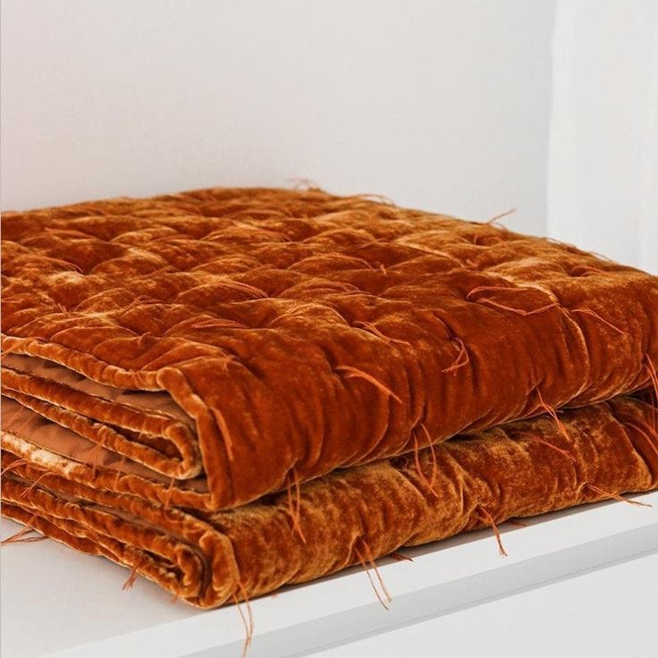 an orange blanket sitting on top of a white shelf