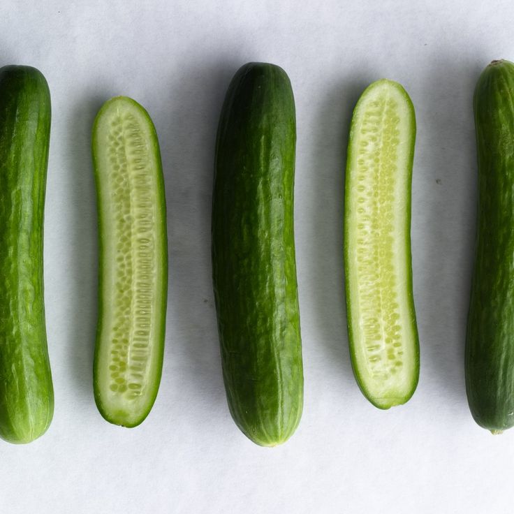 four green cucumbers lined up next to each other