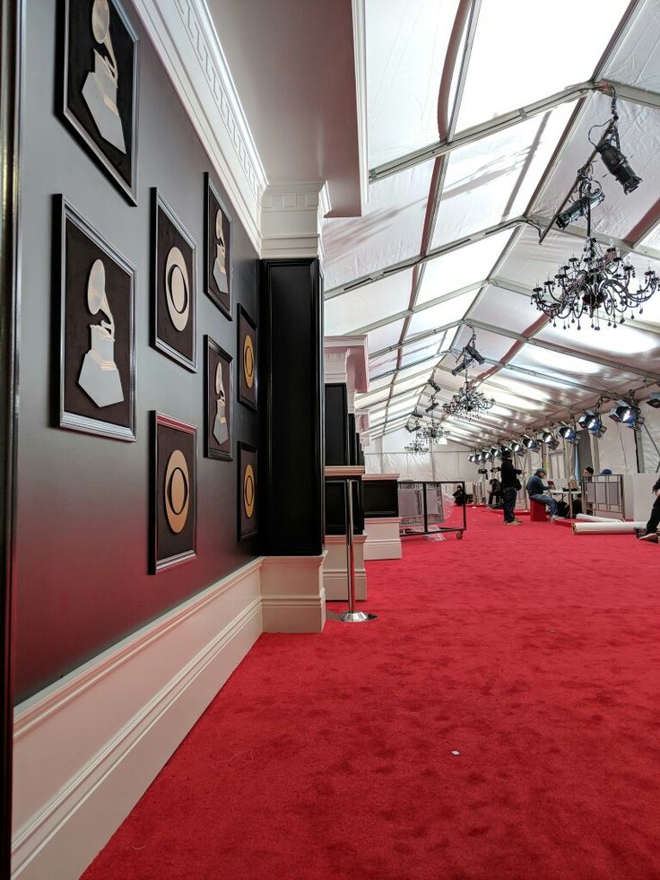 a long red carpeted hallway with pictures on the wall and chandeliers hanging from the ceiling