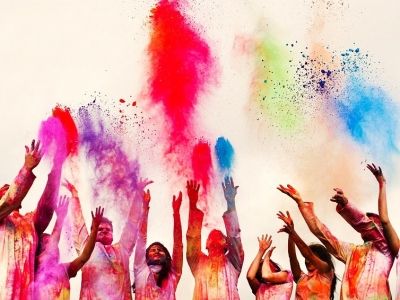 a group of people are throwing colored powder in the air and celebrating with each other