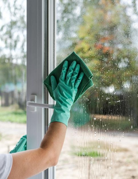 a person in green gloves cleaning a window