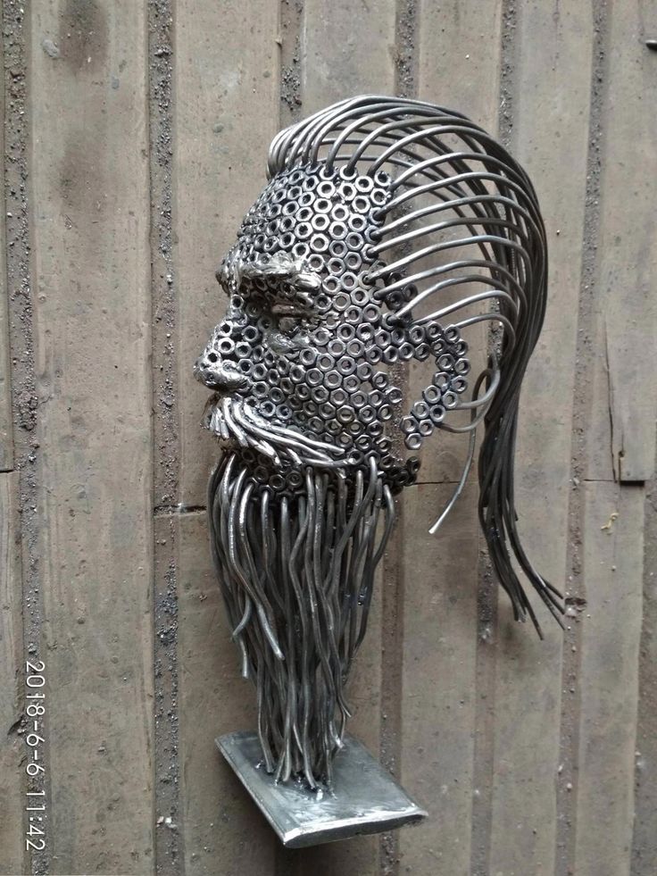 a metal sculpture of a man's head with long hair on top of a stand