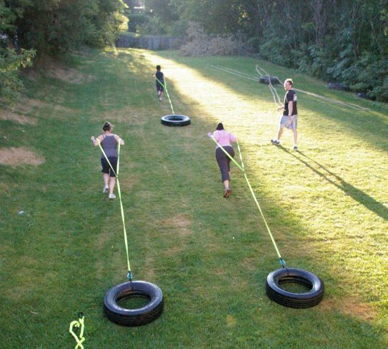 several people are playing tugo ball in the grass with two large tires on each side