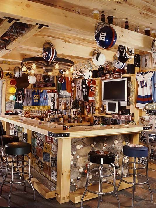 a bar with several sports memorabilia hanging from the ceiling and two stools in front of it