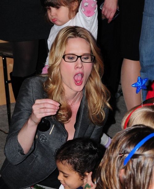 a woman with her mouth open and tongue out in front of some children at a party