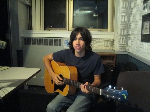 a man sitting in a chair holding an acoustic guitar