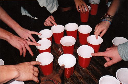 a group of people sitting around a table with red cups on top of each other